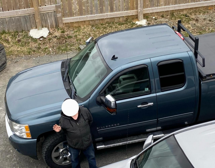 Photo d'un homme, le visage caché, à côté d'une camionnette Chevrolet Silverado bleue.