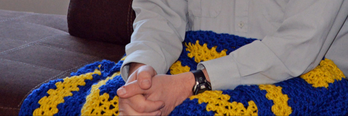 A man's hands on a blue and yellow blanket.