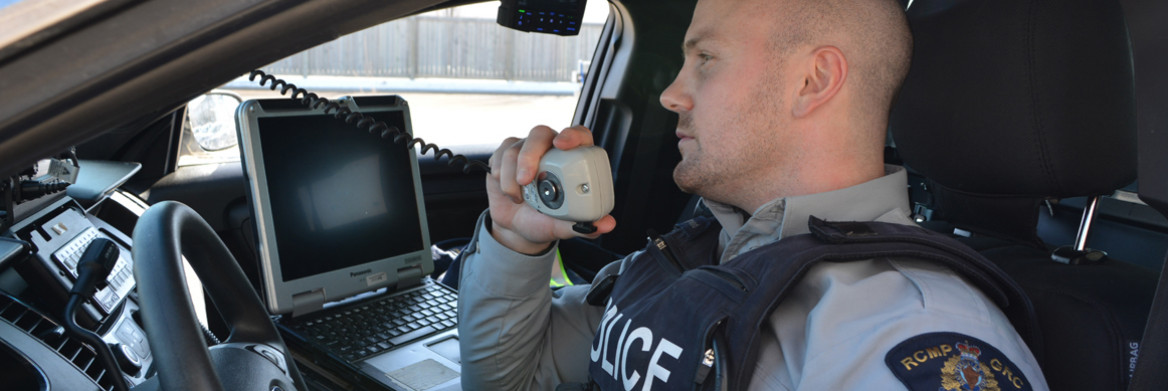 A male RCMP officer sits in a police vehicle.