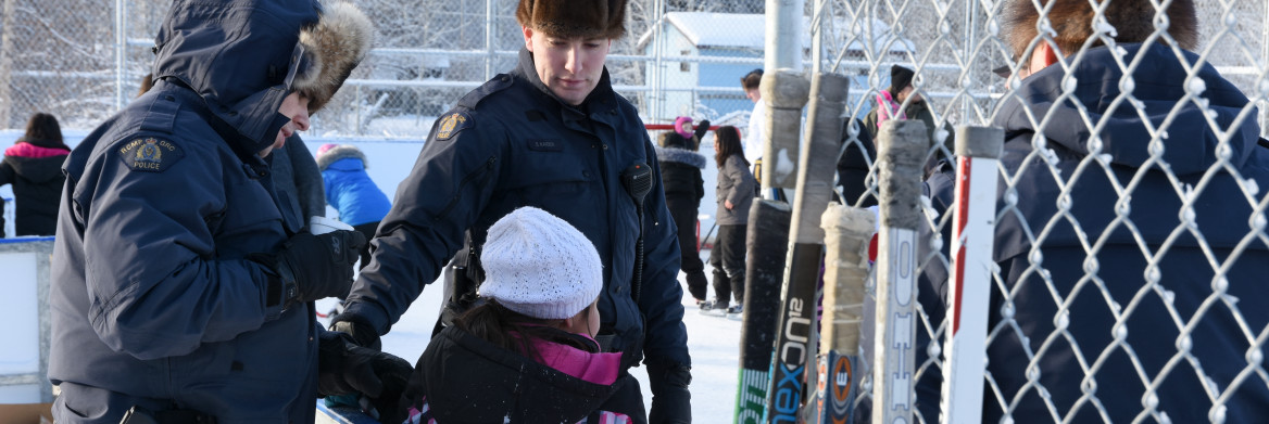 A RCMP officer helps a young skater. 
