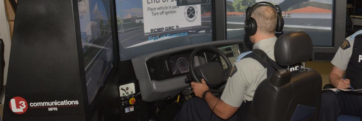 A cadet grips a steering wheel while seated in a virtual reality driver-training console.