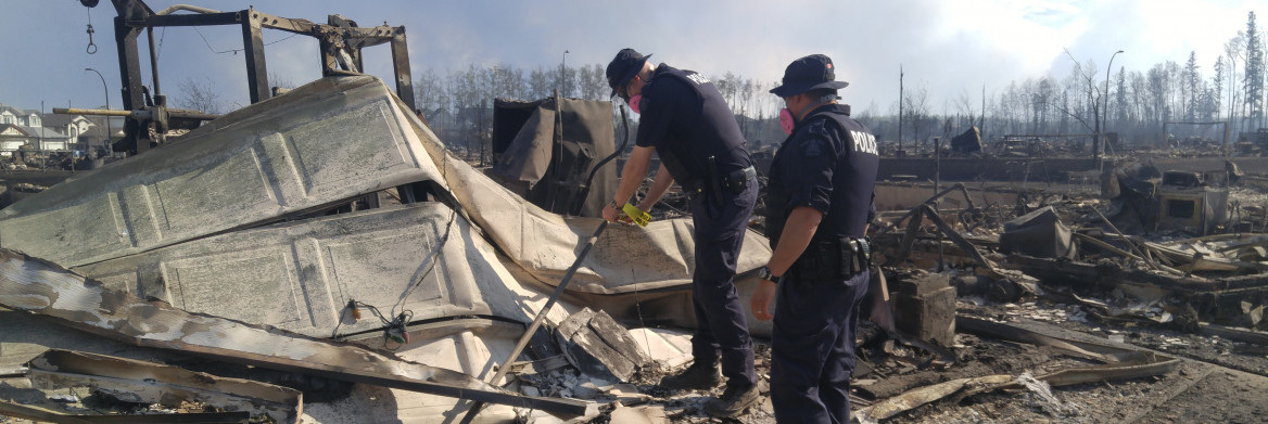 Two male police officers at the site of a burned down house