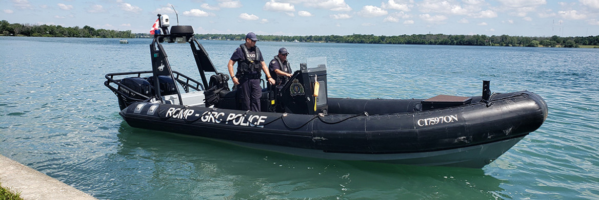 A boat in the water with two male RCMP officers onboard.