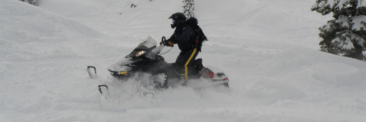 An RCMP officer drives a snowmobile in fresh snow.