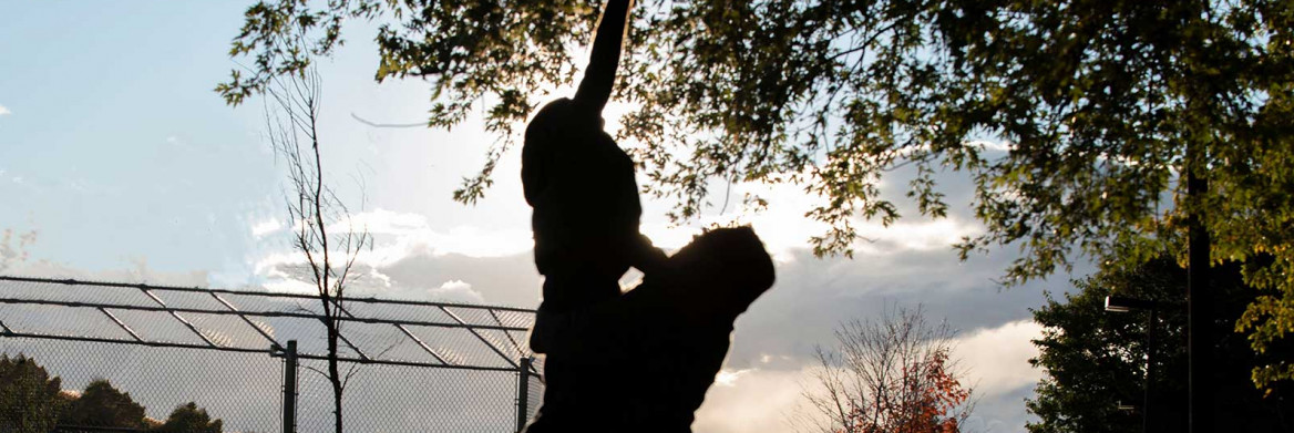 A silhouette of a woman holding up a child in a park.